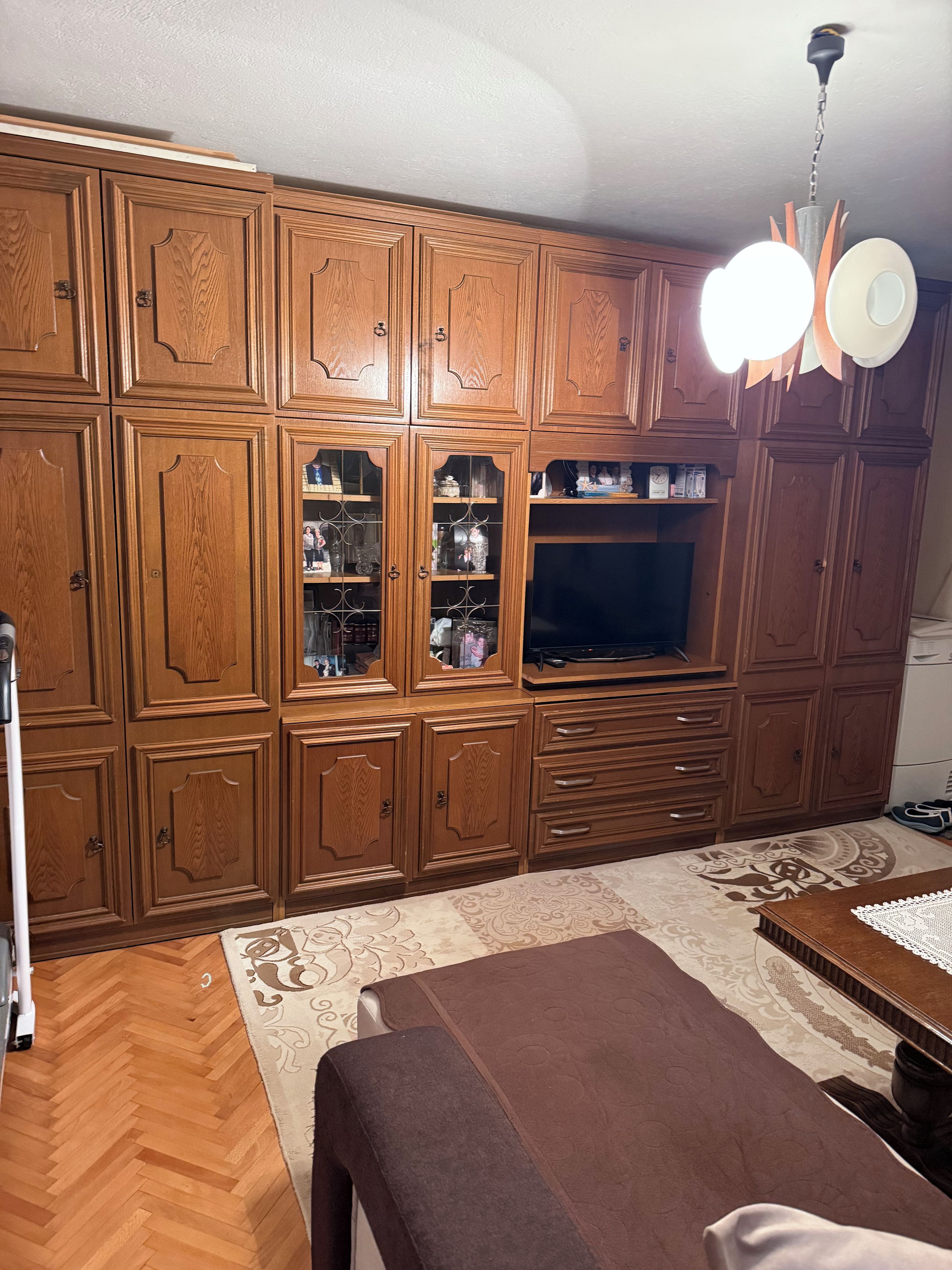 Quarto com armários de madeira, televisão e tapete estampado.