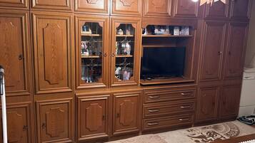 Quarto com armários de madeira, televisão e tapete estampado.