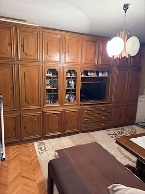 Quarto com armários de madeira, televisão e tapete estampado.