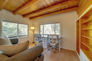 A room with a wooden ceiling, two windows, a desk with a chair, a sofa, and a lamp. - Cozy Prescott Cabin, Surrounded By Ponderosa Pines (Prescott)
