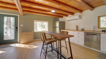 A modern kitchen with wooden beams, a dining area with bar stools, a refrigerator, and a dishwasher.