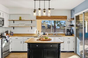 A modern kitchen with a central island, wooden shelves, a built-in oven, and a large window. - Private Pool > Putting Green > GameRoom > Fire Pit > Outdoor Movies (Mesa)