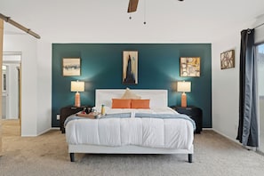 A bedroom with a bed, two bedside tables, a nightstand, a window with curtains, and artwork on the walls. - Private Pool > Putting Green > GameRoom > Fire Pit > Outdoor Movies (Mesa)