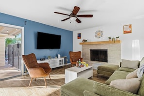 A modern living room with a flat-screen TV, a fireplace, and a ceiling fan. - Private Pool > Putting Green > GameRoom > Fire Pit > Outdoor Movies (Mesa)