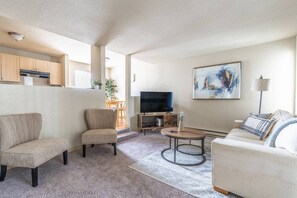 A living room with a sofa, armchair, coffee table, and TV. - Centrally Located 1 Bedroom (Seattle)