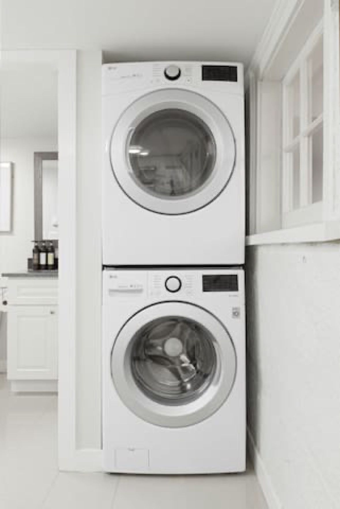 A stacked washer and dryer unit in a room with white walls and a tiled floor.