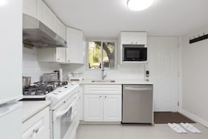 Une cuisine moderne avec des meubles blancs, un lave-vaisselle en acier inoxydable et un four à micro-ondes.