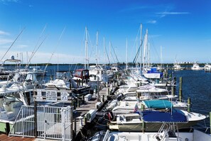 A marina with multiple boats docked, a wooden pier, and a clear blue sky. - Closest to Jetty Park — Pool & Sundeck, 24/7 Staff, Front & Back Decks · Unit D (Fort Pierce)