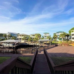 A resort with multiple buildings, a wooden boardwalk, and palm trees. - HIGH TIDE - SUN, SAND & SOUTHERN CHARM
CANAL FRONT- BOAT DOCK- POOL (Mexico Beach)