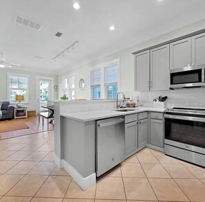 A modern kitchen with grey cabinetry, a central island, and a built-in oven. - HIGH TIDE - SUN, SAND & SOUTHERN CHARM
CANAL FRONT- BOAT DOCK- POOL (Mexico Beach)