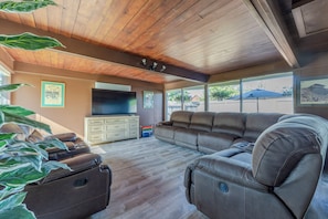 A spacious living room with a wooden ceiling, a large flat-screen TV, a brown leather sofa, and a small table with drawers. - New Listing in Eugene's highly sought after "Ferry Street Bridge" neighborhood. (Eugene)