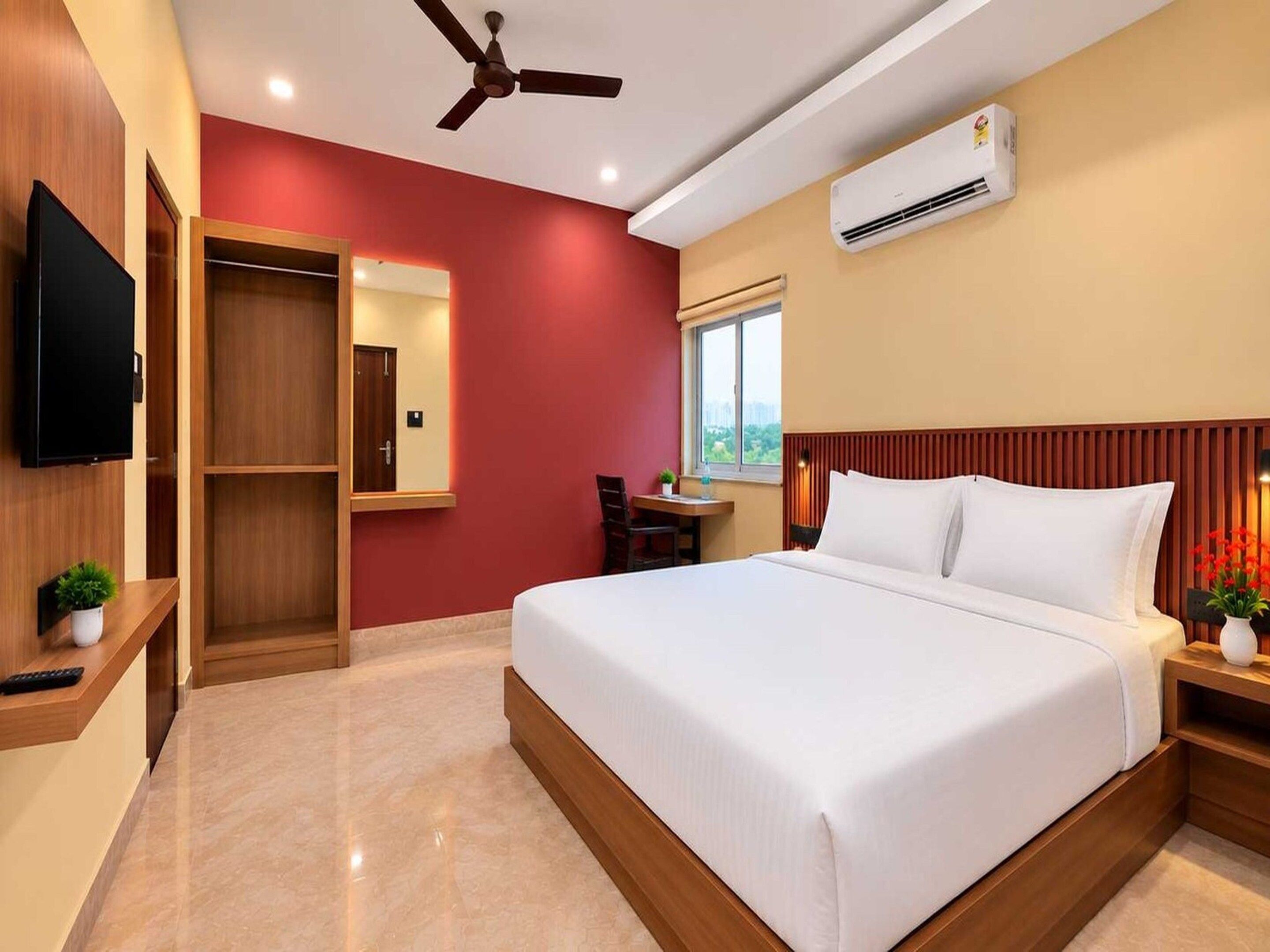 A hotel room with a bed, a television, a desk, and a window.