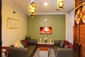 A living room with two sofas, a coffee table, a fireplace, and a wall clock. - Bethel Residence; Private 1-bedroom home in Kampala-free WiFI, Netflix, parking (Kampala)