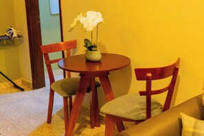 A dining area with a round table, two wooden chairs, and a vase with white flowers. - Bethel Residence; Private 1-bedroom home in Kampala-free WiFI, Netflix, parking (Kampala)