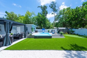 A residential backyard with a swimming pool, a covered patio area, and a well-maintained lawn. - Charlotte Ave Coastal Retreat Private Pool Fire Pit Backyard Lounge (Sarasota)