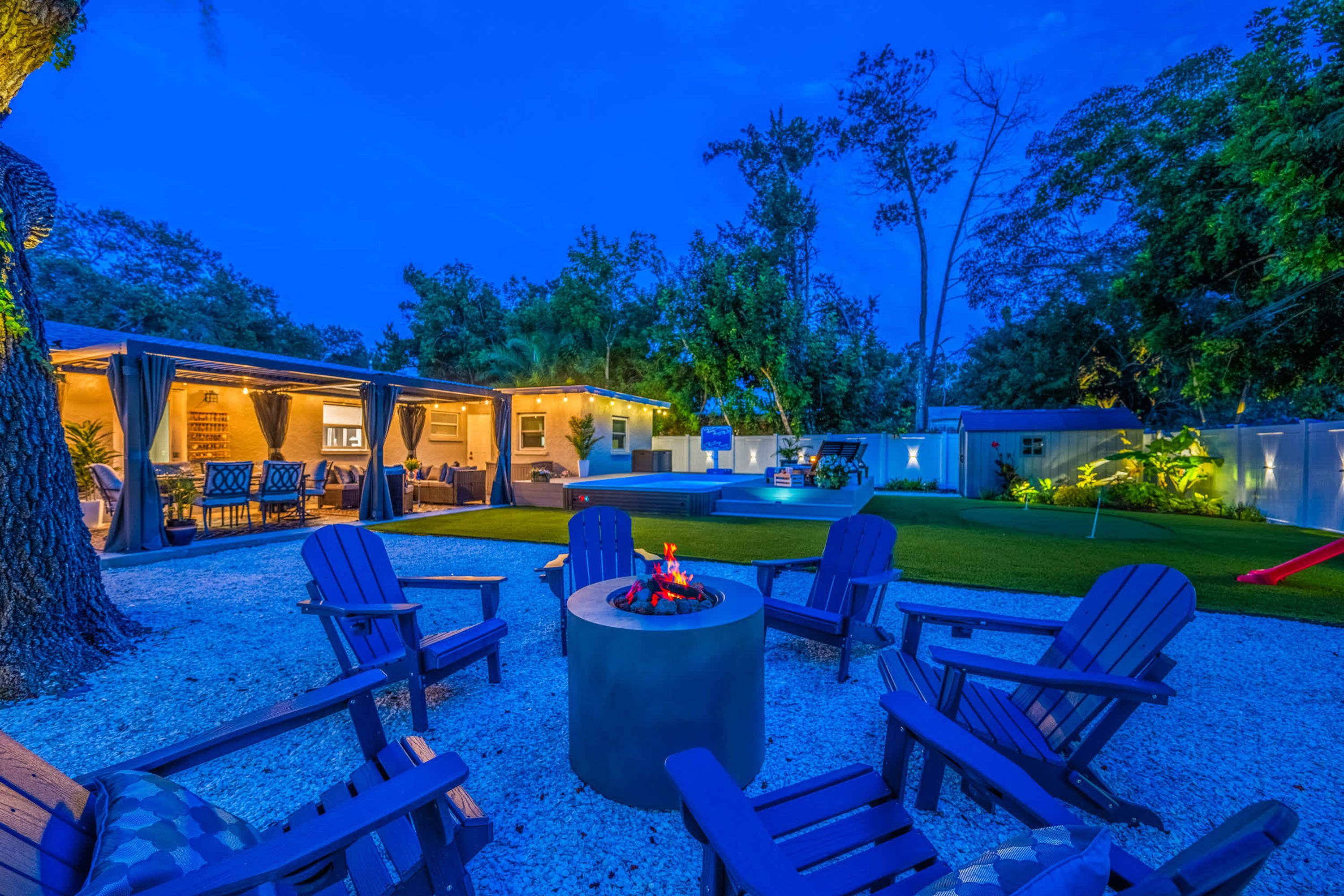 A backyard with outdoor seating, a fire pit, and a covered patio area.