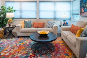A living room with two sofas, a coffee table, and a colorful rug. - Charlotte Ave Coastal Retreat Private Pool Fire Pit Backyard Lounge (Sarasota)