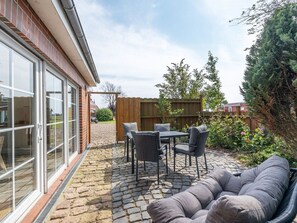 A patio with a table and chairs, a sofa, and a wooden fence. - Holiday Apartment With 1 Bedroom (Westerdeichstrich)