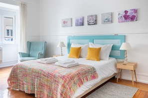A neatly made bed with a colorful blanket, a blue headboard, and two bedside lamps. - Casa da Avenida II Lisboa (Lisbon)