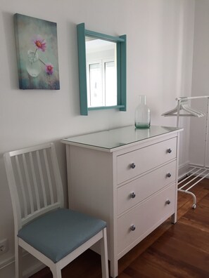 A white dresser with drawers, a mirror with a teal frame, and a chair with a blue cushion. - Casa da Avenida II Lisboa (Lisbon)