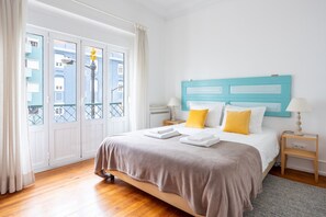 Ein Hotelzimmer mit Bett, Nachttisch, Lampe und Blick auf Gebäude durch das Fenster.