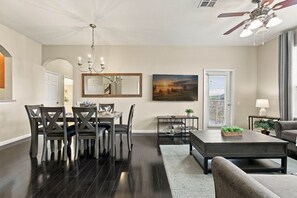 Un salon moderne avec un coin repas, un grand tableau et un ventilateur de plafond.