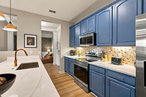 A modern kitchen with blue cabinets, stainless steel appliances, and a marble countertop. - Luxury 3BR, Modern Design, Lake Views, Vista Cay (Orlando)