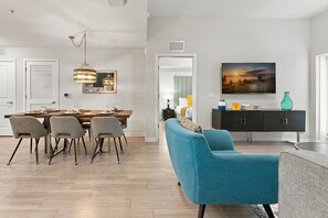Ein modernes Wohnzimmer mit Essbereich, einer Couch, einem Fernseher und einem Gemälde an der Wand.