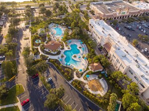 An aerial view of a resort with multiple swimming pools, a parking lot, and a large building adjacent to the pools. - Comfortable 3BR condo at Orlando Best Location (Orlando)