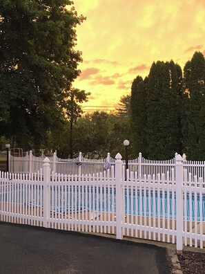 A fenced swimming pool with a white picket fence, surrounded by trees and a cloudy sky. - Charming 4-bedroom house with POOL in peaceful New Columbia (New Columbia)