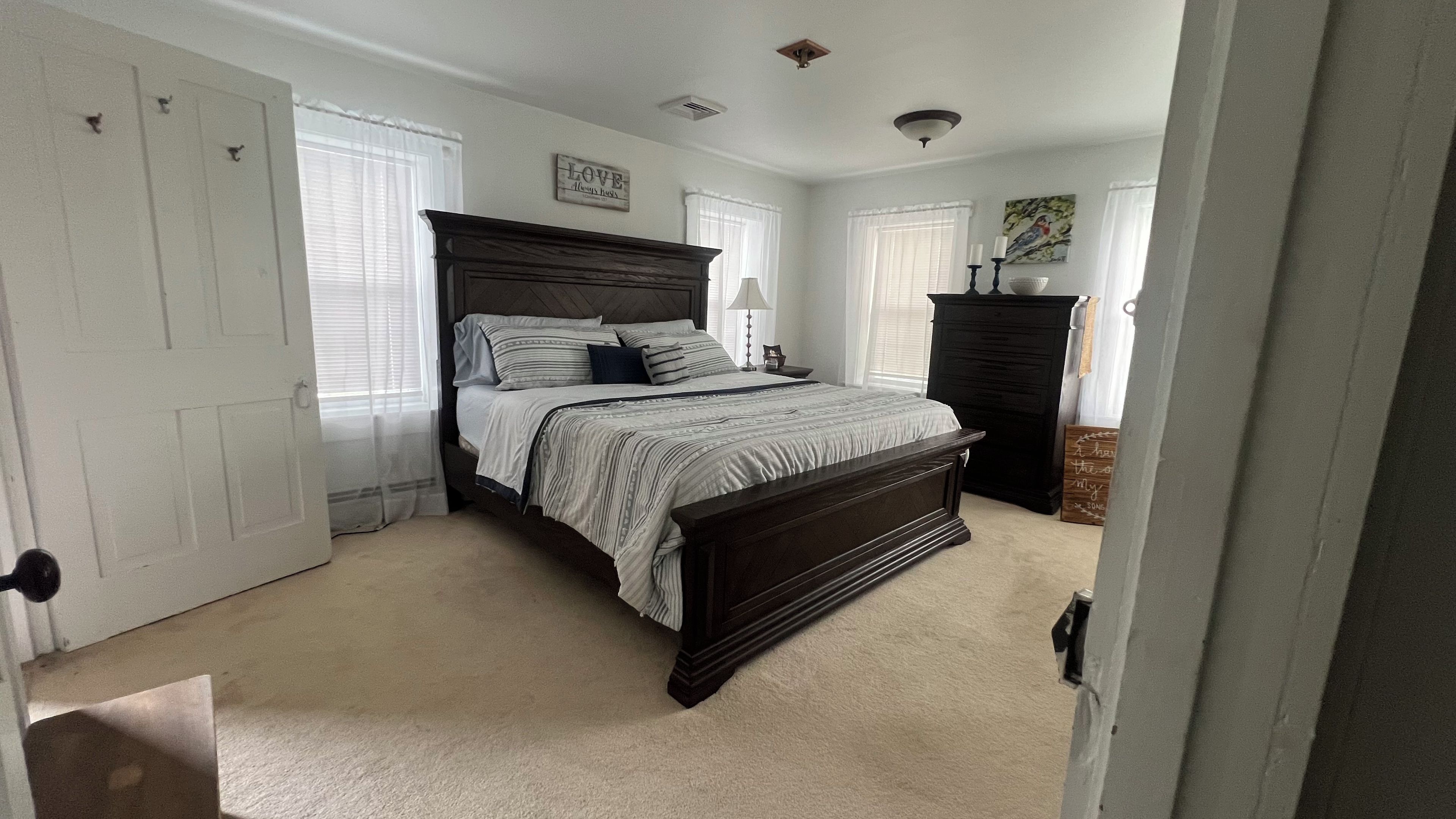 Quarto com cama, penteadeira, mesa de cabeceira e luminária na parede.