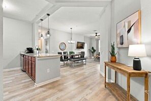 A modern kitchen with a central island, dining area with a table and chairs, and a living space with a sofa and TV. - 3BR at Vista Cay, where Comfort meets Convenience (Orlando)