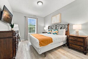 A bedroom with a bed, bedside tables, a dresser, a window with curtains, and a painting on the wall. - 3BR at Vista Cay, where Comfort meets Convenience (Orlando)