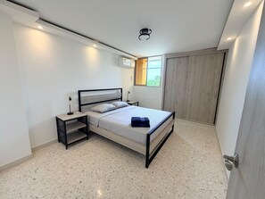 A modern bedroom with a bed, bedside tables, a wardrobe, and a window. - Cozy 3-bedroom en La Zona Rosa de Barranquilla (Barranquilla)