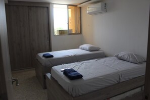 Ein Zimmer mit zwei Einzelbetten, einem Kleiderschrank, einer Klimaanlage und einem Fenster mit Blick.