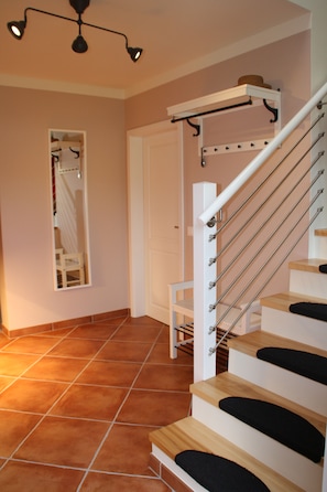 A staircase with a handrail, a door, and a mirror on the wall. - Cozy vacation home with a fireplace on a large garden lot, with a view of Lilienstein (Rathmannsdorf)