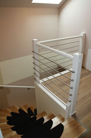 A white metal rack with multiple shelves, likely for storage, in a room with wooden flooring and white walls. - Cozy vacation home with a fireplace in a large garden, with a view of Lilienstein   (Rathmannsdorf)