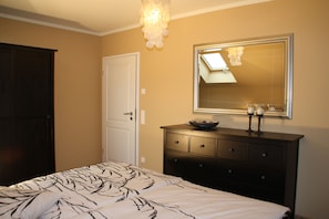 Een slaapkamer met een bed, een dressoir en een spiegel.