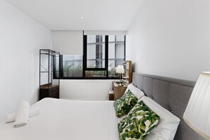 A modern bedroom with a large bed, a nightstand, a lamp, and a window with a view of buildings. - High-rise 1-bed Apartment Near Brisbane CBD (Brisbane)