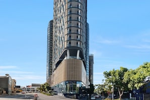 A modern high-rise building with a curved facade, large windows, and a prominent entrance. - High-rise 1-bed Apartment Near Brisbane CBD (Brisbane)