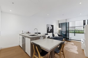 A modern kitchen with a dining area, a sofa, and a large window. - High-rise 1-bed Apartment Near Brisbane CBD (Brisbane)
