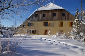 Un bâtiment en bois doté de nombreuses fenêtres et dont le toit est recouvert de neige.