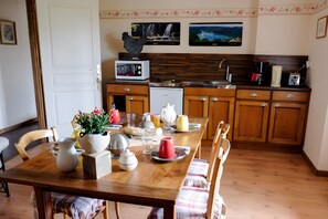 Una cucina con mobili in legno, un tavolo da pranzo apparecchiato con piatti, tazze e un vaso di fiori.