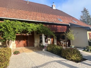 Ein Haus mit rotem Ziegeldach, einer Veranda mit Pflanzen und einem gepflasterten Auffahrt.