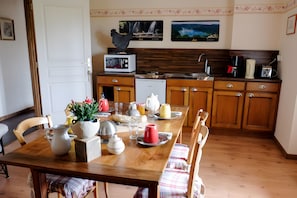 A kitchen with wooden cabinets, a dining table set with plates, cups, and a vase of flowers.