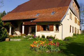 Ein zweistöckiges Haus mit Satteldach, einer Veranda und einem Garten mit Tulpen.