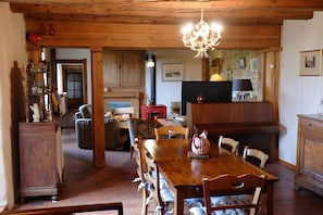 Un comedor amplio con una mesa de madera, sillas y una araña.