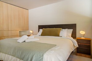 A neatly made bed with white linens and a green throw blanket, two bedside lamps, and a wooden wardrobe in a hotel room. - Large Terrace Studio · Selected Design (H02) (Providencia)