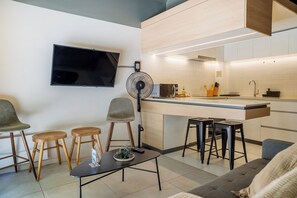 A modern kitchen with a flat-screen TV, a fan, and bar stools. - Large Terrace Studio · Selected Design (H02) (Providencia)