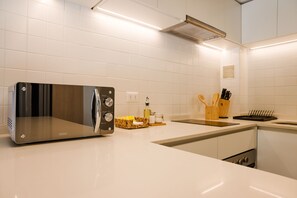 A modern kitchen with white tiles, a stainless steel toaster oven, a knife block, and a sink. - Large Terrace Studio · Selected Design (H02) (Providencia)